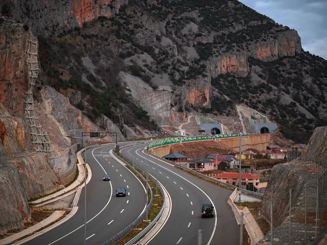 A highway through a rock cutting, with twin tunnel portals ahead